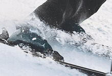 Close-up of skier's ski boots and skis in motion on snow, capturing the dynamic movement of winter sports.