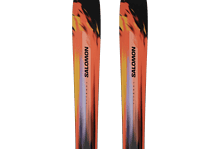 Pair of Salomon skis with vibrant orange, black, and yellow design, ideal for winter skiing adventures.