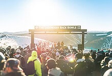 Crowd of skiers and snowboarders at the legendary Back Bowls ski event with scenic mountain views in the background.
